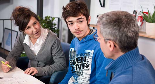 Eine Beratungssituation in der Jugendberufsagentur. Ein junger Mann sitzt mit zwei Fachkrften ber einem Lebenslauf zusammen